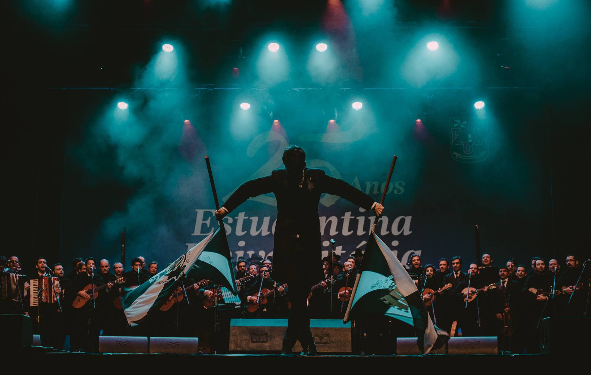The Estudantina Universitária de Lisboa performing on stage — black capes, Portuguese guitar, voices in choir.